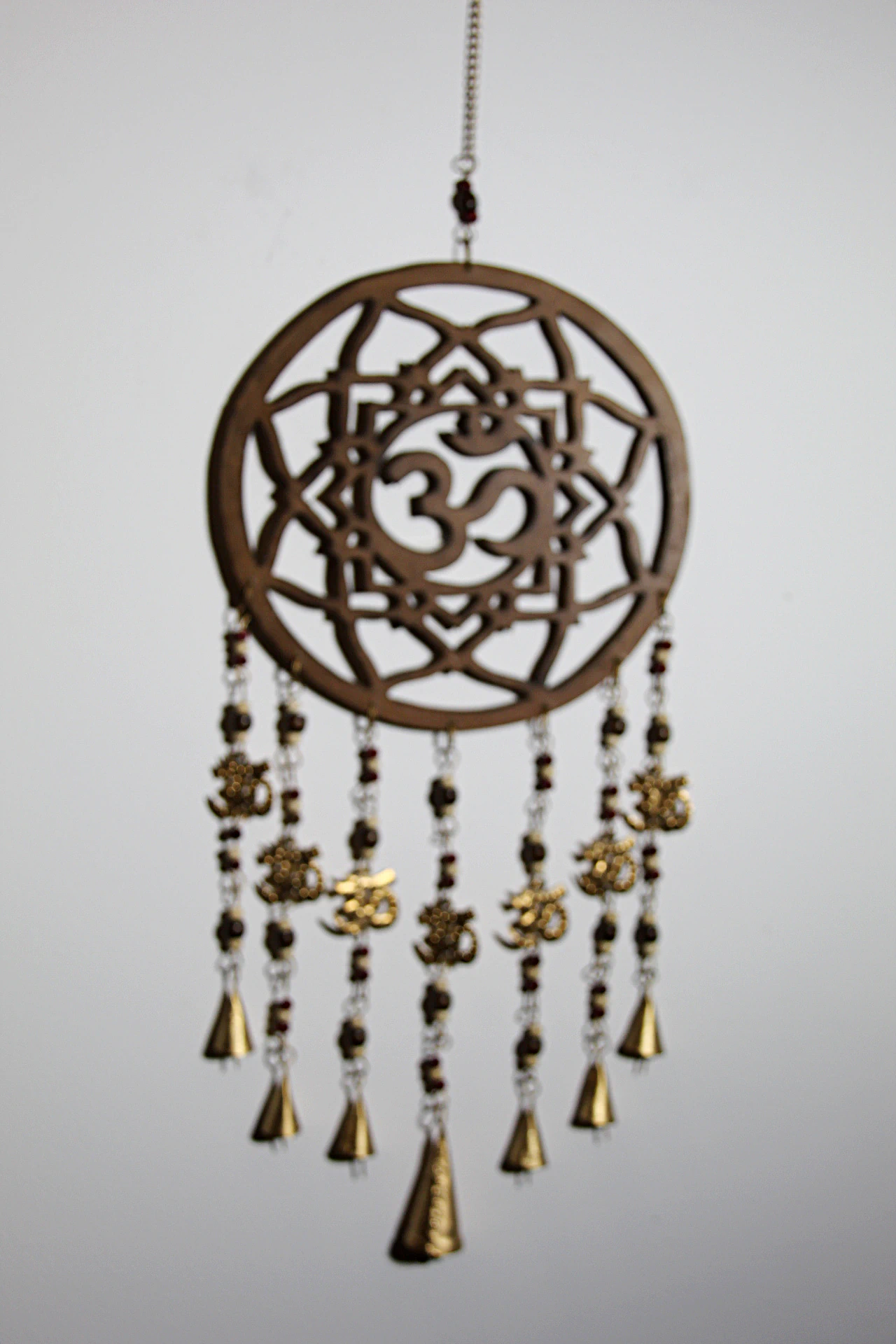 O espanta-espíritos de madeira com o símbolo OM é uma peça tradicional que ajuda a proteger e harmonizar o ambiente. O seu som suave