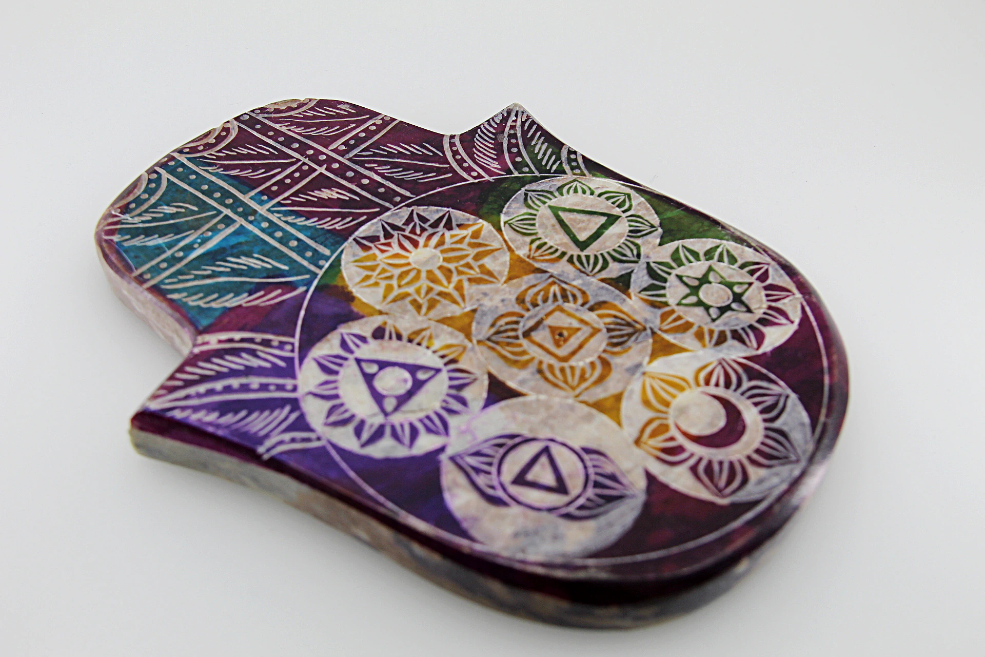 O porta-incenso em pedra de sabão com mão e chakras é uma peça funcional e resistente